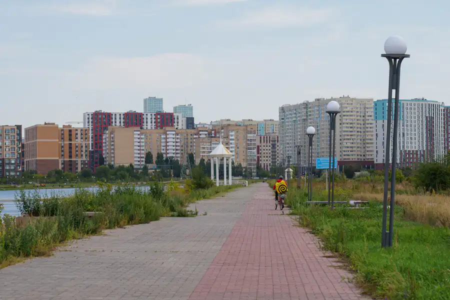 Курьер на велосипеде едет по набережной, Астана